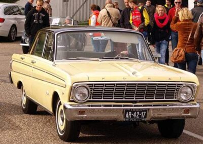 1964 Ford Falcon in yellow, showcasing classic car design, parked among onlookers at an event, highlighting Wilson Auto Repair's restoration expertise.