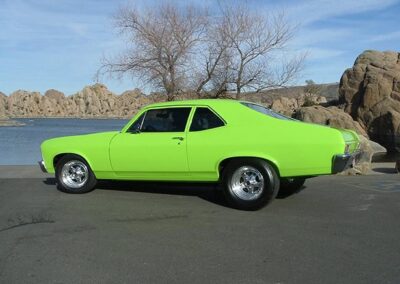 1970 Chevy Nova SS in vibrant green color, showcasing classic car restoration by Wilson Auto Repair, with a scenic backdrop of rocks and water.