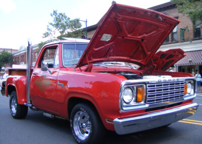 Red Dodge pickup truck with hood raised, showcasing engine, parked on street, highlighting classic car restoration by Wilson Auto Repair.